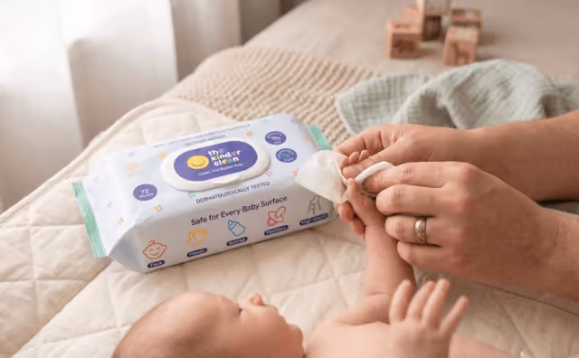 Parent gently wiping a newborn's hand with a Kinder Clean wipe on the changing table